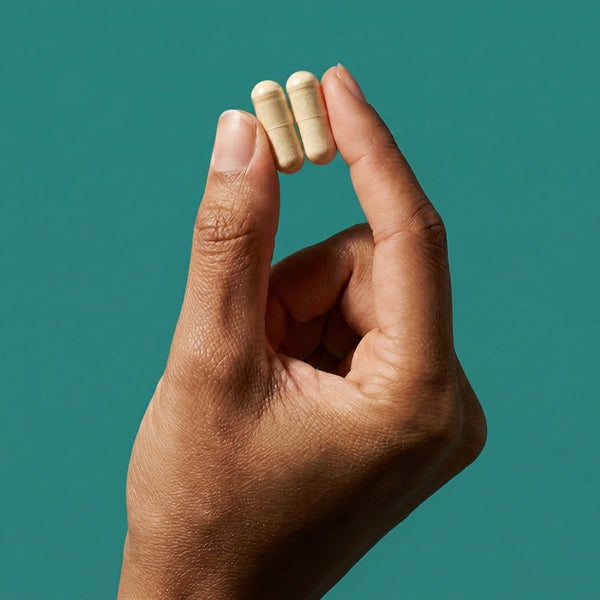 'Hand holding two NCL (Natural Cure Labs) capsules, representing wellness supplementation.'