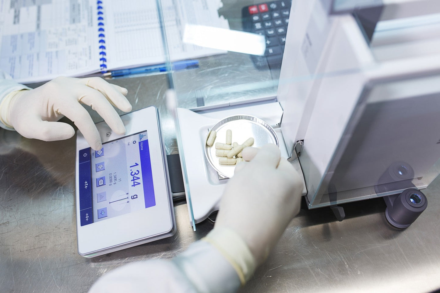 A person's gloved hands operating a digital scale with monolaurin capsules on it, set against a clinical backdrop with a focus on the precision of laboratory work.